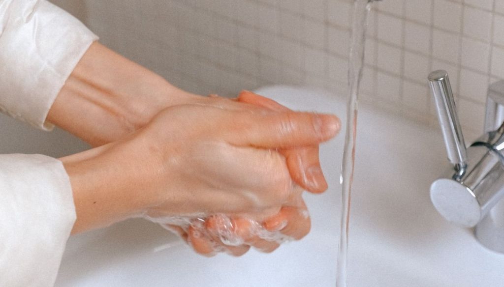 woman washes hands bathroom sink washing hands