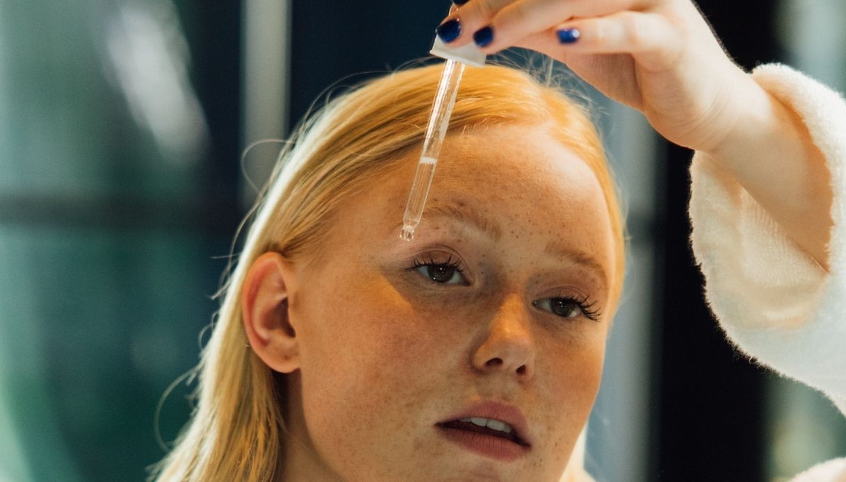 freckled blonde girl applies face serum