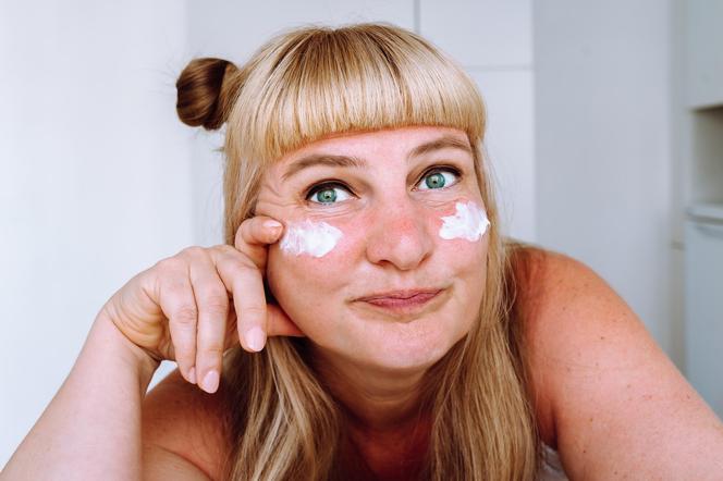 Woman with cream under her eyes smiles